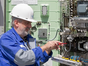 Mitarbeiter arbeitet mit einem Schraubenzieher an einer Anlage mit vielen Kabeln Mitarbeiter arbeitet mit einem Schraubenzieher an einer Anlage mit vielen Kabeln